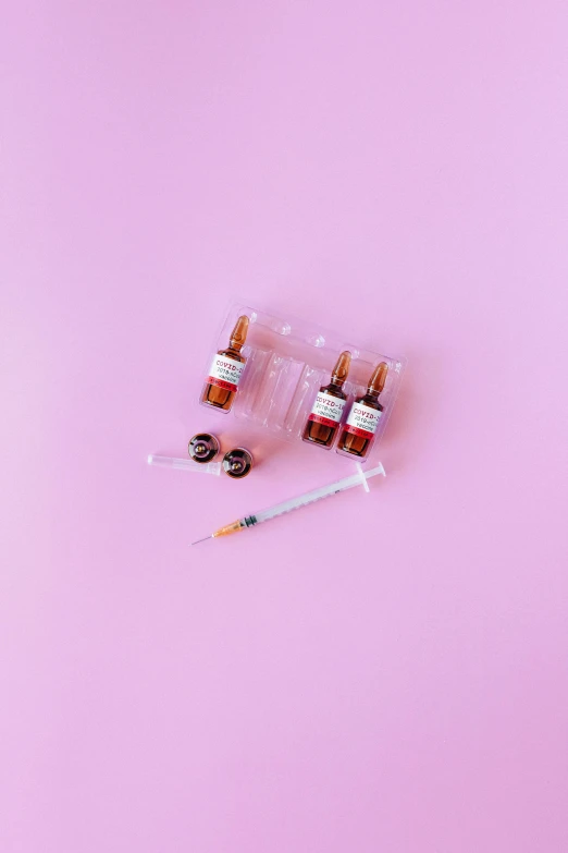 a bottle of medicine and a syll on a pink background, by Julia Pishtar, dau-al-set, syringes, brown and pink color scheme, miniature product photo, set against a white background