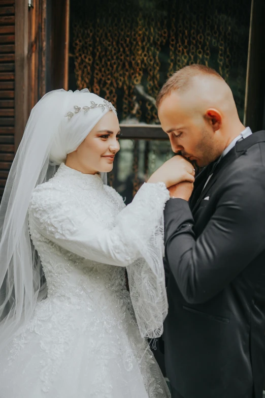 a man standing next to a woman in a wedding dress, inspired by Nadim Karam, hurufiyya, touching heads, muslim, holding hands, day time