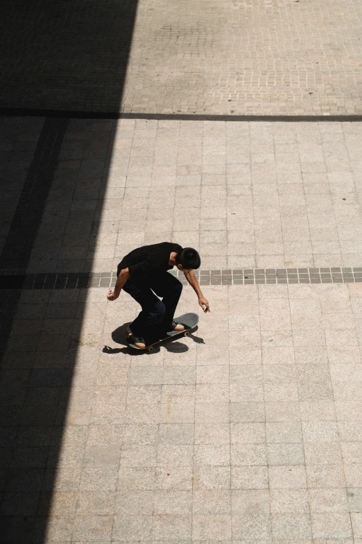a man riding a skateboard down a sidewalk, a picture, by Niko Henrichon, top down view, in a square, low quality photo, back - lit