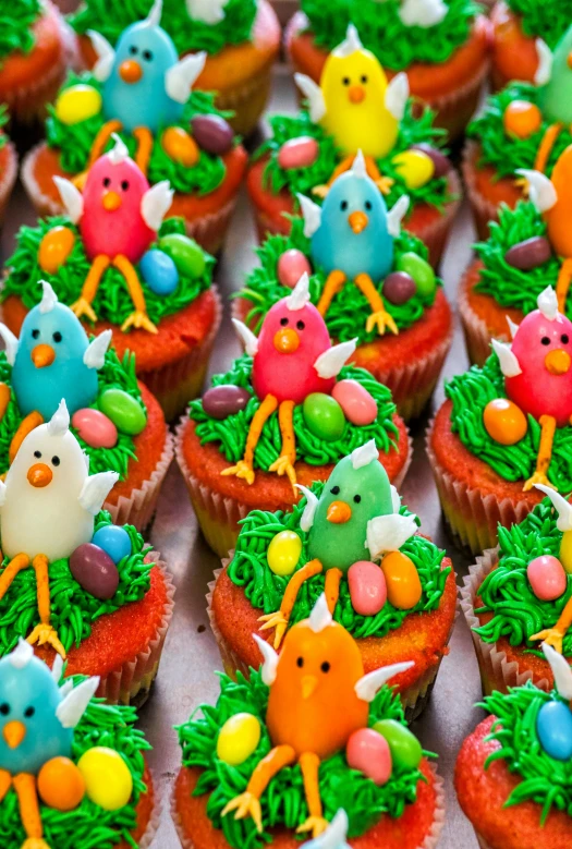 a table topped with lots of cupcakes covered in frosting, inspired by Károly Patkó, with chicks, vibrant vivid colors, zoomed in, may)