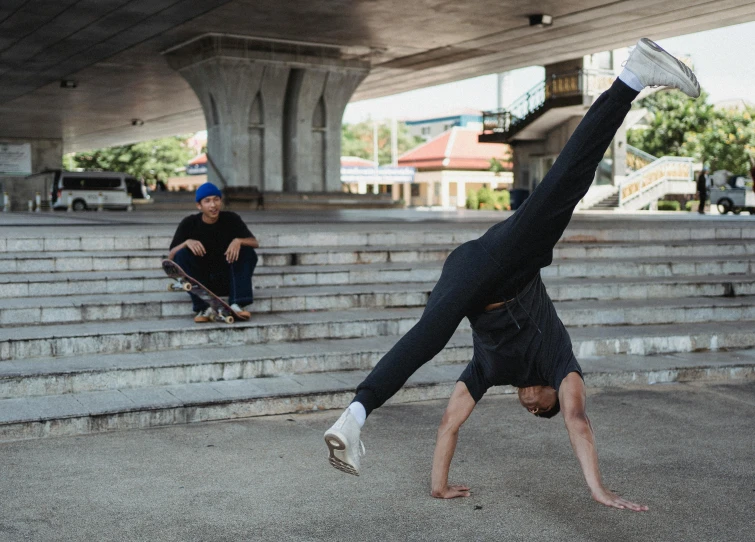 a man doing a handstand in front of a skateboarder, sydney hanson, liam brazier, pixeled stretching, sitting under bridge