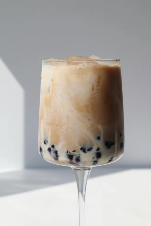 a glass of bubble tea sitting on top of a table, white with black spots, sapphire, 3/4 side view, soymilk