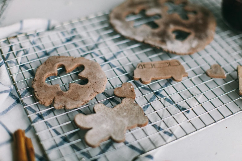 some cookies are sitting on a cooling rack, a picture, by Julia Pishtar, unsplash, folk art, flour dust spray, cut out, shaped derriere, holiday