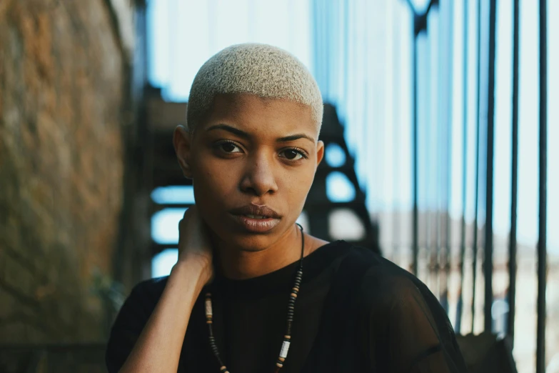 a close up of a person with a necklace on, inspired by Elsa Bleda, pexels contest winner, afrofuturism, short platinum hair tomboy, african american young woman, ochre, portrait of bald