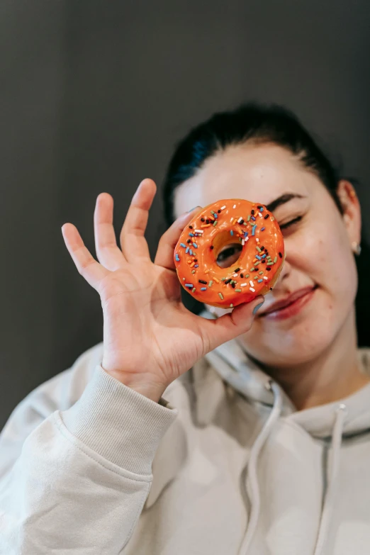 a woman holding a donut with sprinkles on it, trending on pexels, hyperrealism, holding hot sauce, 8 0 mm photo, smirking, scientific photo