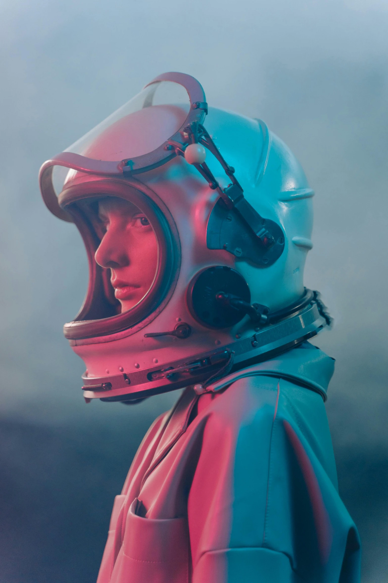 a close up of a person wearing a helmet, an album cover, by Filip Hodas, retrofuturism, beautiful woman in spacesuit, atmospheric cool color - grade, flight suit, futuristic fashion show