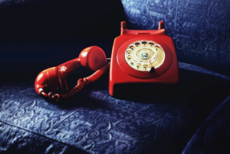 a red telephone sitting on top of a blue couch, dial, analogue photography, hires, telephhoto