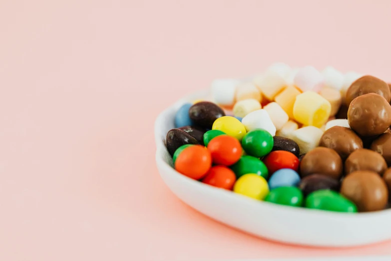 a white bowl filled with assorted candy, by Nicolette Macnamara, pexels, 6 0 s colour palette, profile image, plain background, beans