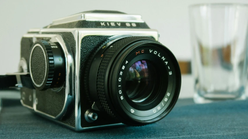 a camera sitting on top of a table next to a glass, by Konrad Witz, unsplash, hyperrealism, medium format. soft light, hasselblad film bokeh, film photography from 7 0 s, lofi