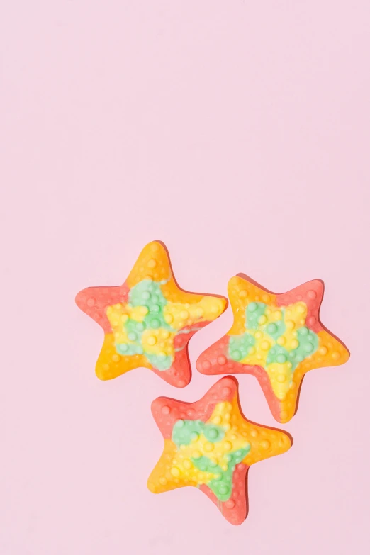 three star shaped sugar cookies on a pink background, a colorized photo, by Julia Pishtar, trending on pexels, pop art, made of multicolored crystals, communist starfish, 1 8, cute colorful adorable