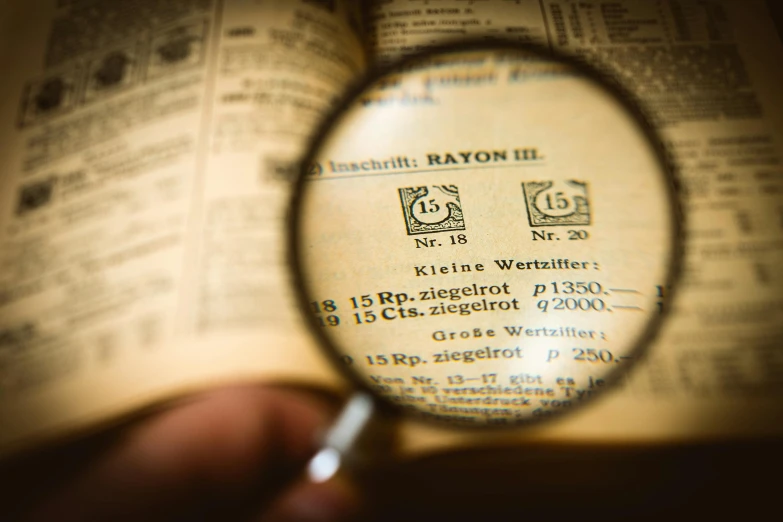 a person holding a magnifying glass over a book, a microscopic photo, pixabay, bauhaus, instagram photo, set in ww2 germany, chemical substances, read a directory book