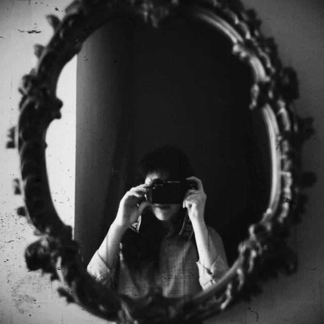 a woman taking a picture of herself in a mirror, a black and white photo, by Emma Andijewska, romanticism, donglu yu, uploaded, # myportfolio, korean artist