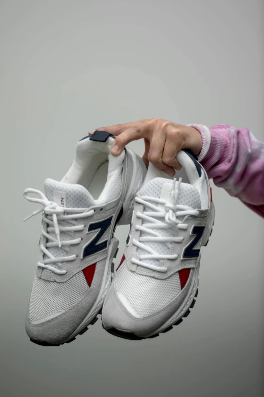 a person holding a pair of white sneakers, hyperrealism, ap news photograph, '0 0 s nostalgia, sports clothing, new balance pop up store