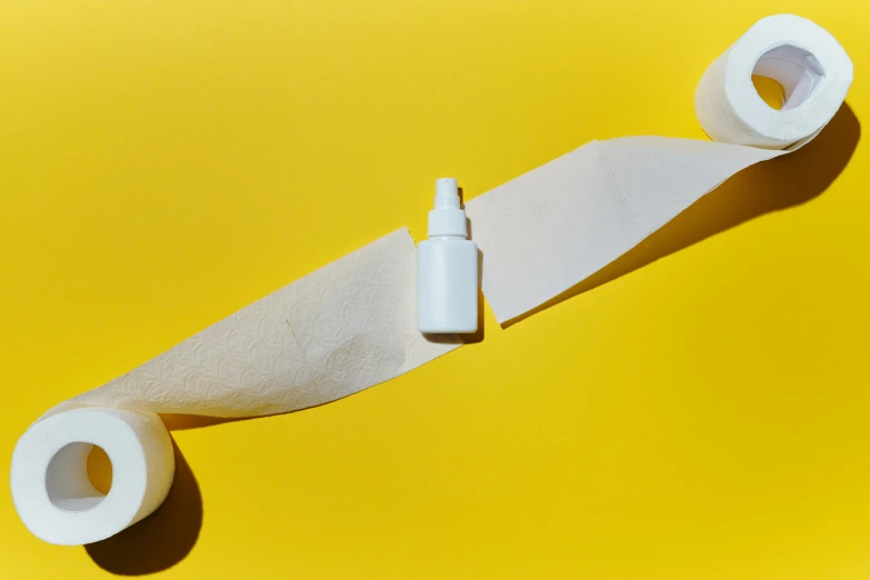 a roll of toilet paper sitting on top of a roll of toilet paper, pexels contest winner, plasticien, on yellow paper, carrying a bottle of perfume, photoshoot for skincare brand, surgical iv drip