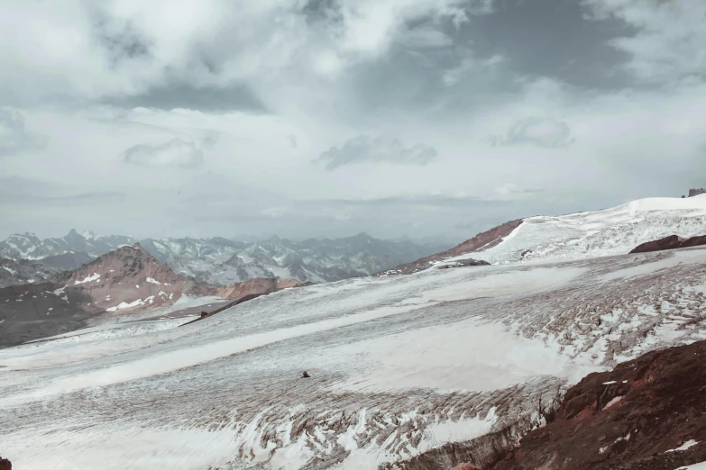 a man standing on top of a snow covered mountain, by Ismail Acar, pexels contest winner, les nabis, muted brown, 4 k cinematic panoramic view, red sand, grey