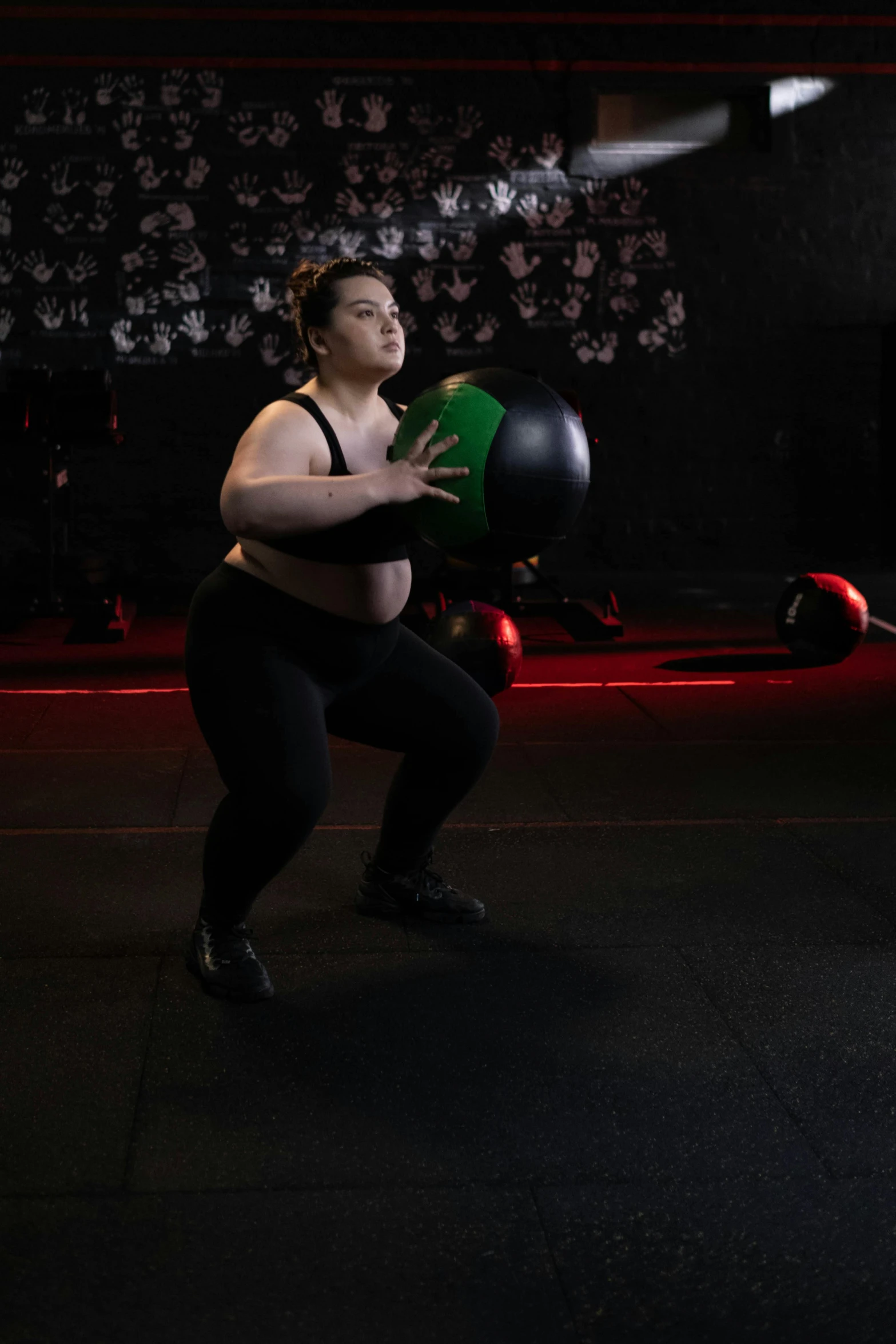 a woman holding a medicine ball in a gym, by Arabella Rankin, happening, dark backdrop, plus-sized, wētā fx, programming