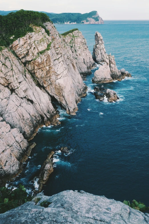a man standing on top of a cliff next to the ocean, pexels contest winner, renaissance, south korea, aerial footage, highly detailed rock structures, full frame image