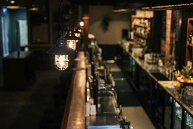 a bar filled with lots of bottles and lights, unsplash, private press, gas lamps, slightly minimal, looking from side, dingy lighting