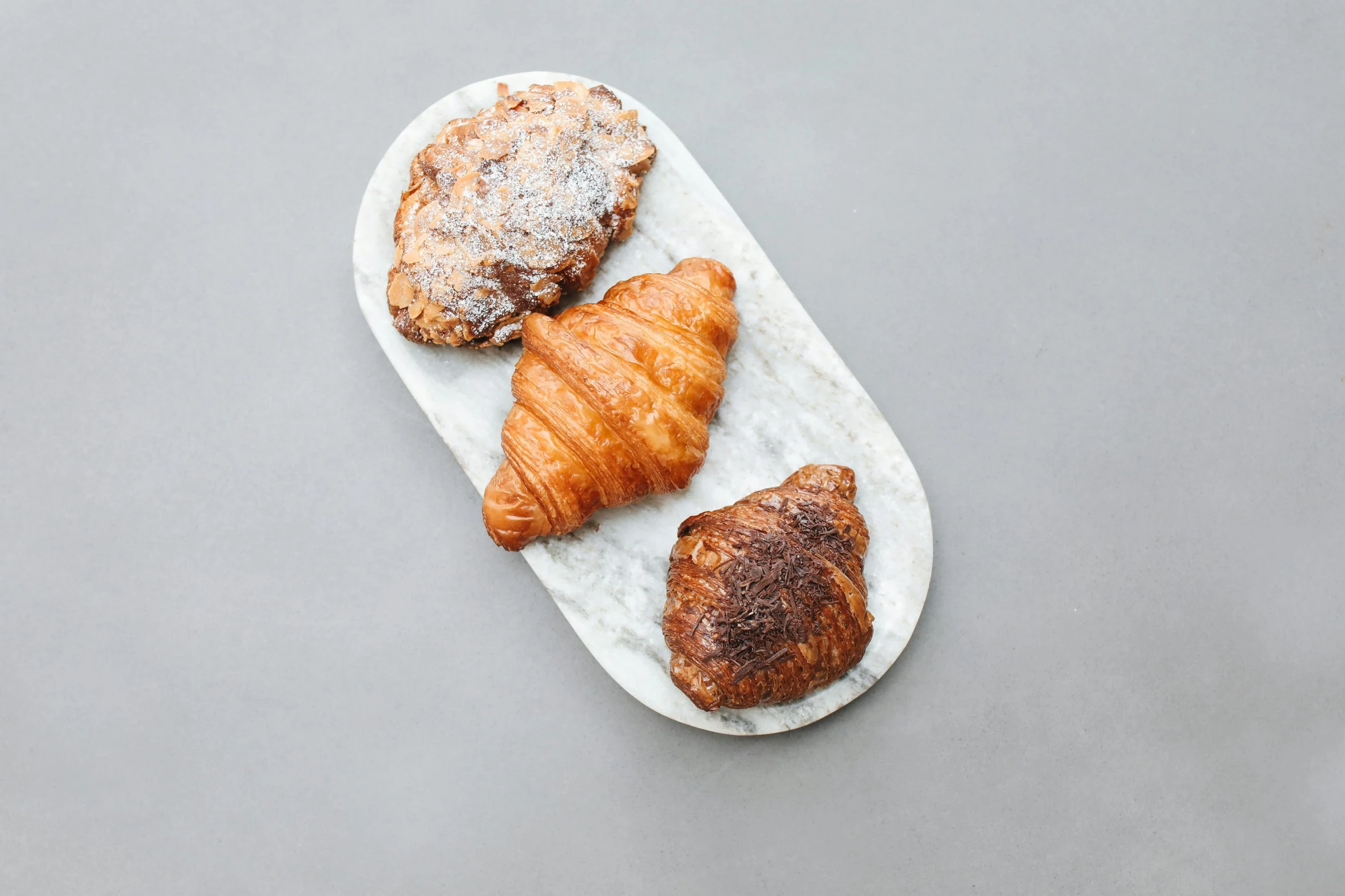 a white plate topped with croissants and pastries, inspired by Richmond Barthé, unsplash, made of carrara marble, 3 - piece, grain”, various sizes