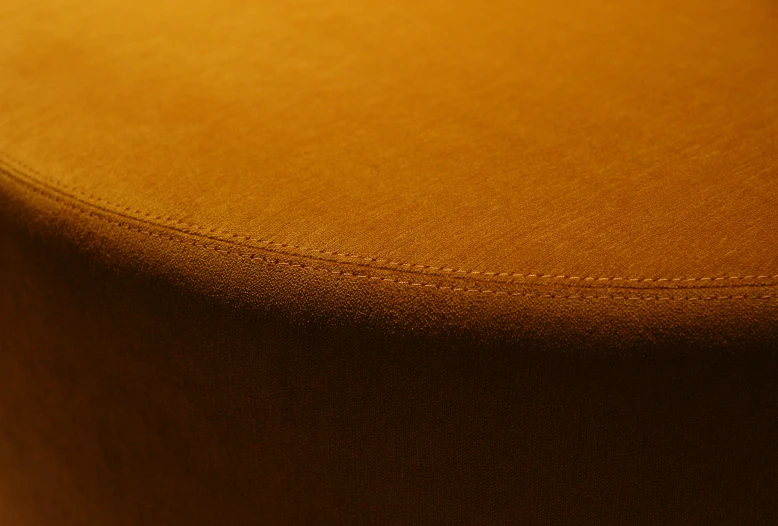 a brown ottoman sitting on top of a wooden floor, yellow ochre, 8k fabric texture details, detailed product shot, curved