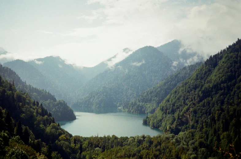 a large body of water sitting on top of a lush green hillside, an album cover, inspired by Zhang Kechun, unsplash contest winner, renaissance, carpathian mountains, lake in the forest, 2000s photo, 2022 photograph
