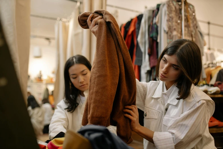 two women are working in a clothing store, by Nina Hamnett, trending on pexels, wearing a brown cape, sydney hanson, digital image, thumbnail