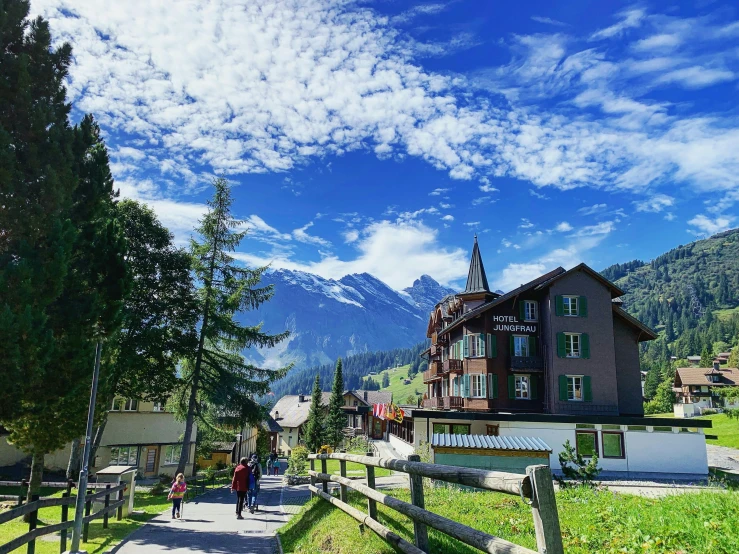 a couple of people that are walking down a path, by Werner Andermatt, hurufiyya, clear blue skies, in town, 🚿🗝📝, chalet