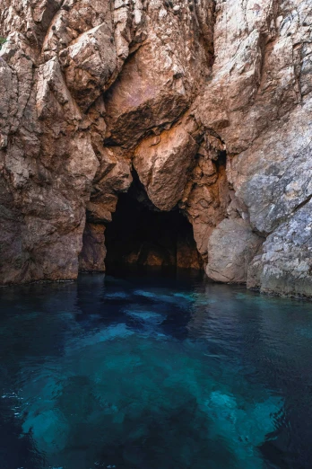 a cave in the middle of a body of water, dark blue water, piroca, australian, head straight down