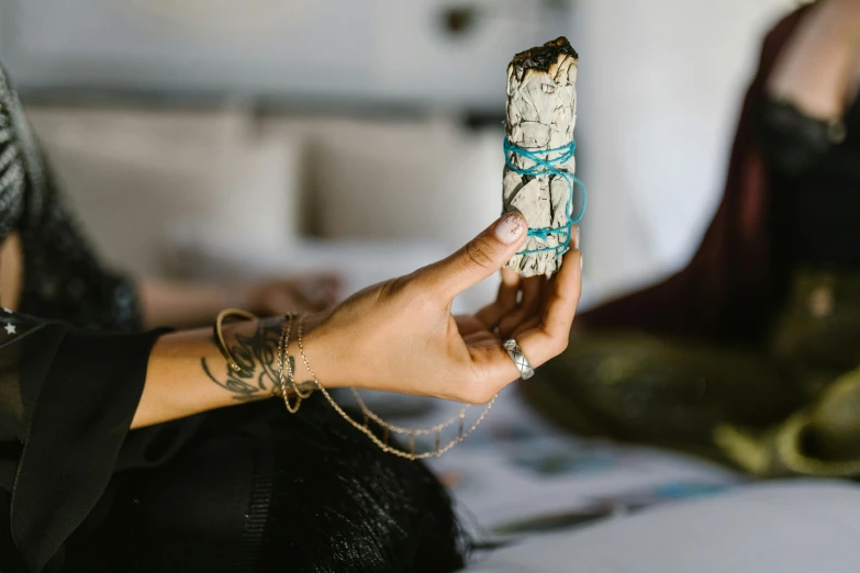 a woman sitting on a bed holding a smudling smudling smudling smudling smudling smudling smud, a marble sculpture, trending on pexels, shamanic poste, crystal column, justina blakeney, with an intricate