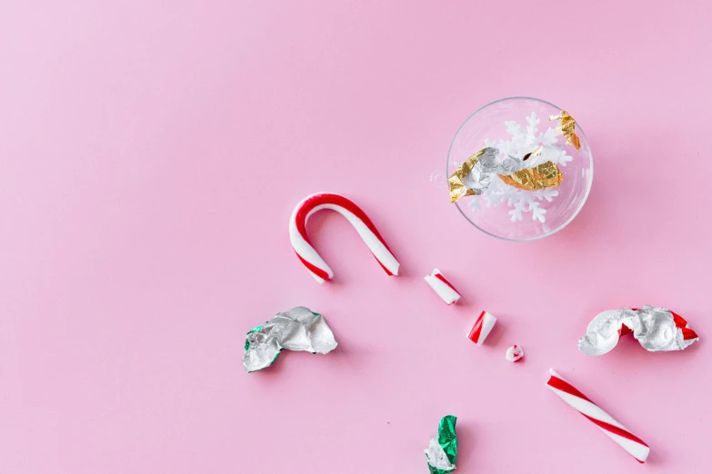 candy canes and candy canes on a pink surface, by Julia Pishtar, shattered, foil, ornament, drink