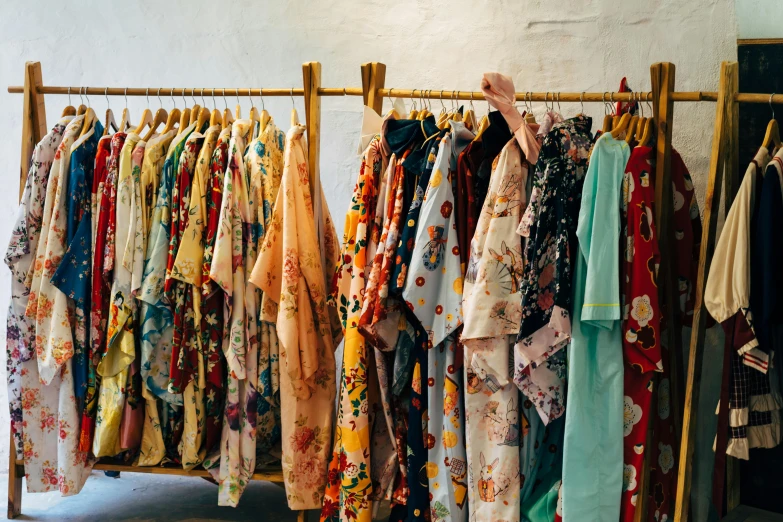 a bunch of clothes hanging on a rack, trending on unsplash, mingei, brocade robes, floral clothes, wearing a baggy pajamas, quirky shops