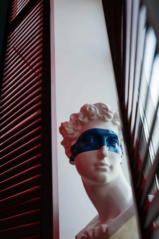 a statue of a woman with blindfolds in front of a window, inspired by Sir Jacob Epstein, mannerism, prussian blue and venetian red, stripe over eye, jimin\'s grecian nose, in a hotel hallway