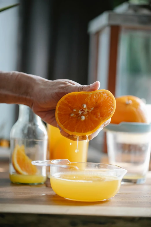 a person squeezing an orange into a bowl, spilling juice, uncrop, uncropped, recipe