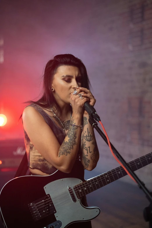 a woman singing into a microphone while holding a guitar, inspired by Hannah Frank, antipodeans, with tattoos, hazy atmosphere, promo image, pouting