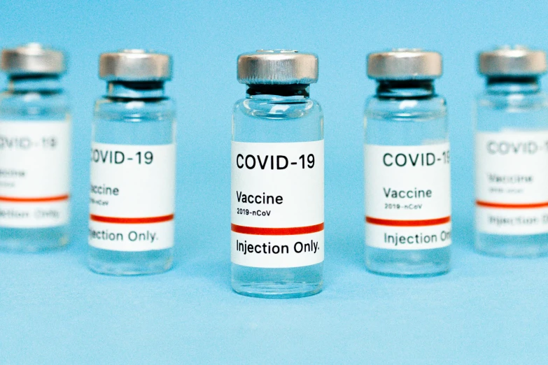 a row of vaccine vials sitting on top of a blue surface, a picture, visual art, 3 - piece, covid, label, 1 6 x 1 6