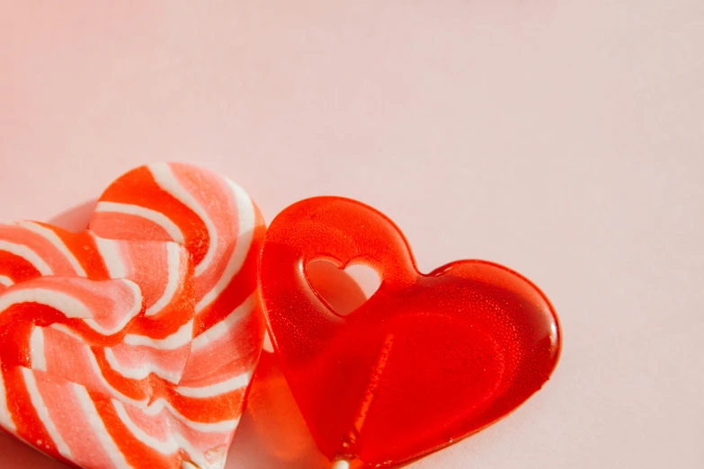 a couple of lollipops sitting next to each other, by Emma Andijewska, pexels, glass-cast heart, 15081959 21121991 01012000 4k, soft red tone colors, thumbnail