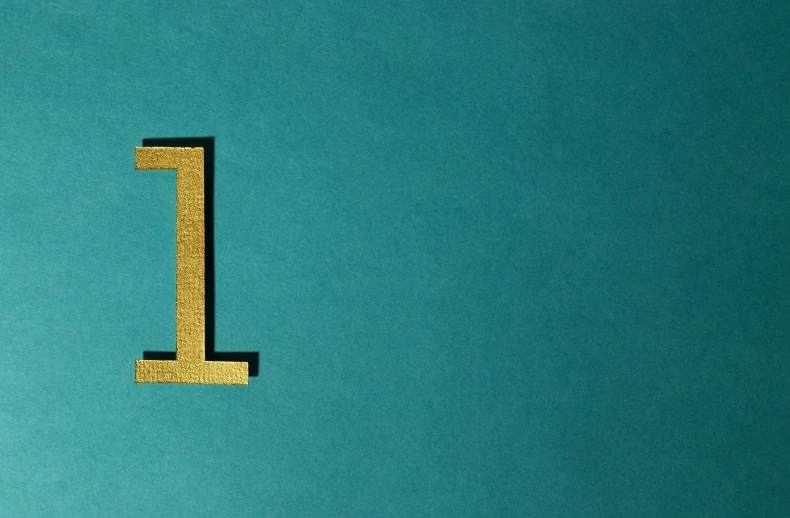 a close up of the letter l on a blue background, an album cover, trending on pixabay, private press, golden number, gold and teal color scheme, still from a wes anderson film, black and teal paper