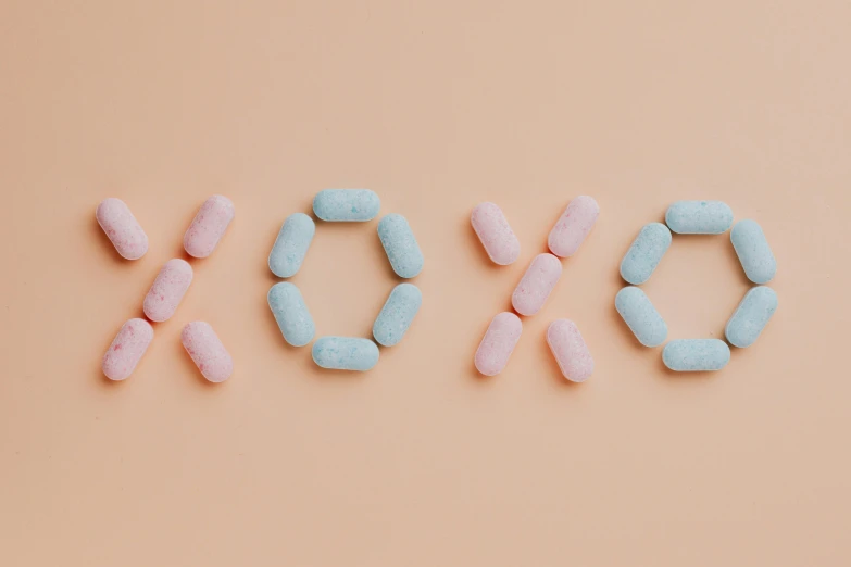 pink and blue pills arranged in the shape of xoxo, a digital rendering, trending on pexels, antipodeans, toned orange and pastel pink, jen atkin, kiss, 20 years old