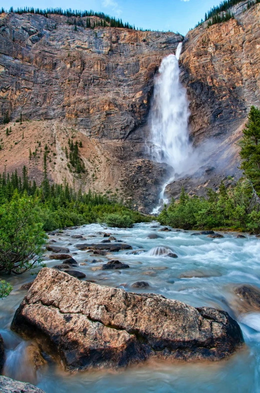 a waterfall flowing down the side of a mountain, by Doug Wildey, rocky mountains and a river, sandfalls, stunnig