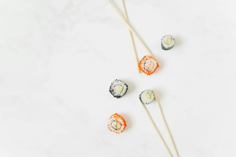 a white table topped with sushi and chopsticks, inspired by Maki Haku, unsplash, sprinkles, on a white background, unfinished, thumbnail