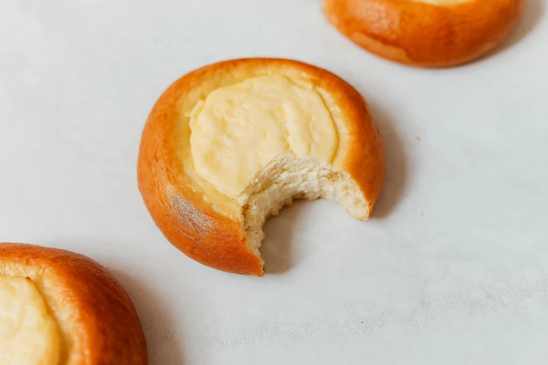 a close up of a doughnut with a bite taken out of it, inspired by Kanō Shōsenin, shin hanga, cheeses, on a pale background, loaves, heise jinyao