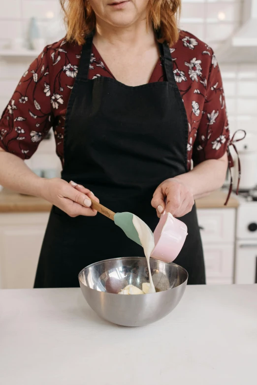 a woman in an apron mixing ingredients in a bowl, a colorized photo, trending on pexels, detailed product image, cake, australian, spatula