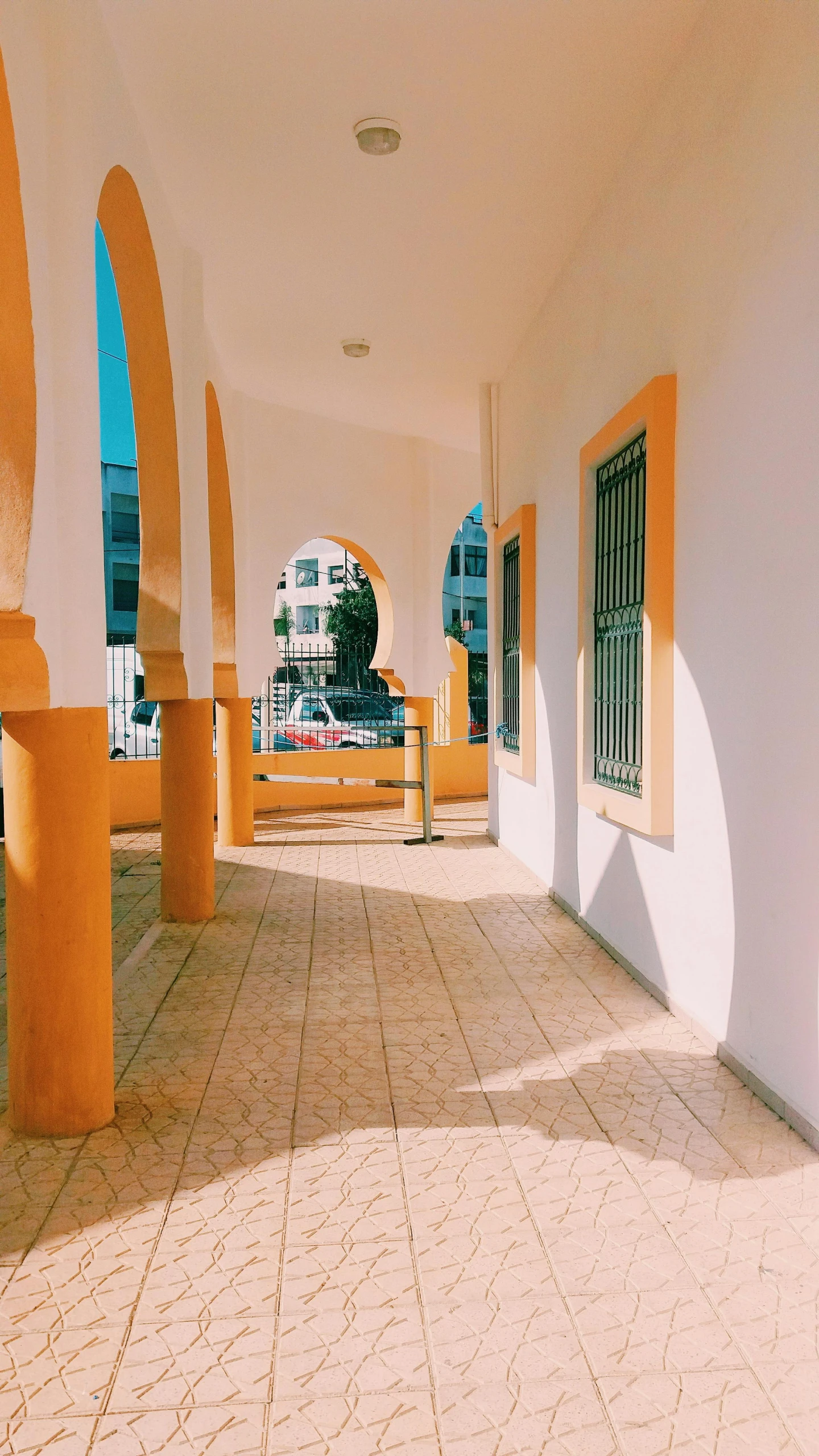 a white and yellow building with columns and windows, a photo, by Ahmed Yacoubi, unsplash, light and space, summer street near a beach, 80s interior with arched windows, 15081959 21121991 01012000 4k, taken on iphone 1 3 pro