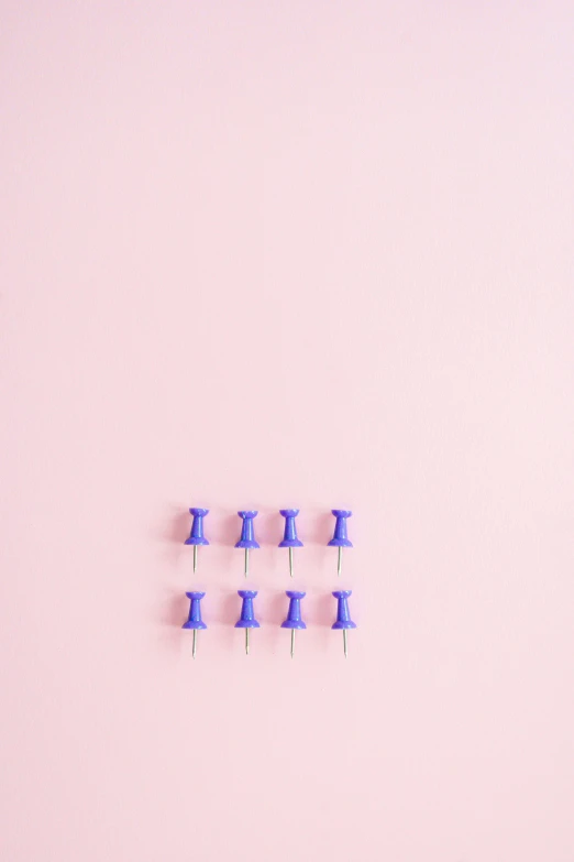 a group of blue push pins sitting on top of a pink surface, a minimalist painting, inspired by Yves Klein, trending on unsplash, dividing it into nine quarters, lavender, ecommerce photograph, minimalist wallpaper