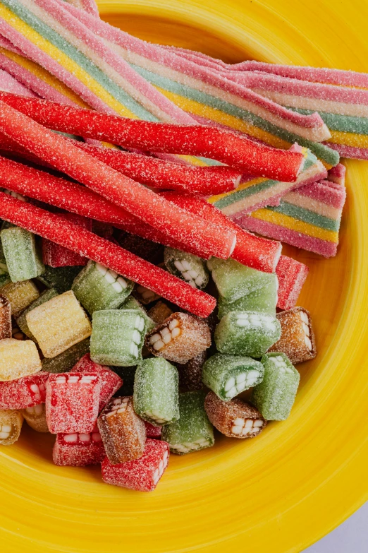 a yellow bowl filled with assorted candies, inspired by david rubín, red green, jackstraws, medium close up, corduroy