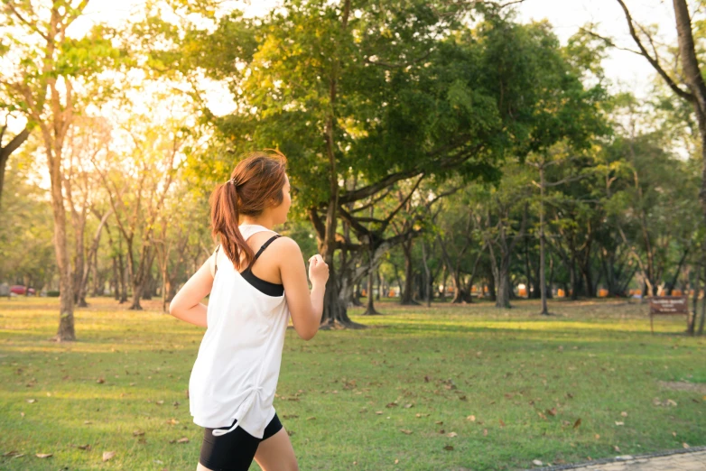 a woman running in a park on a sunny day, by Emma Andijewska, shutterstock, early evening, avatar image, green spaces, white