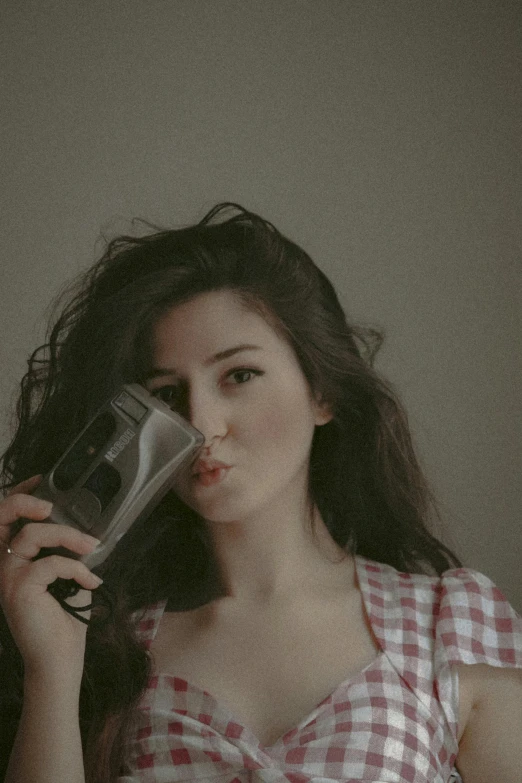 a woman holding a camera up to her face, windblown dark hair, retro aesthetic, hairdryer, amy sol in the style of