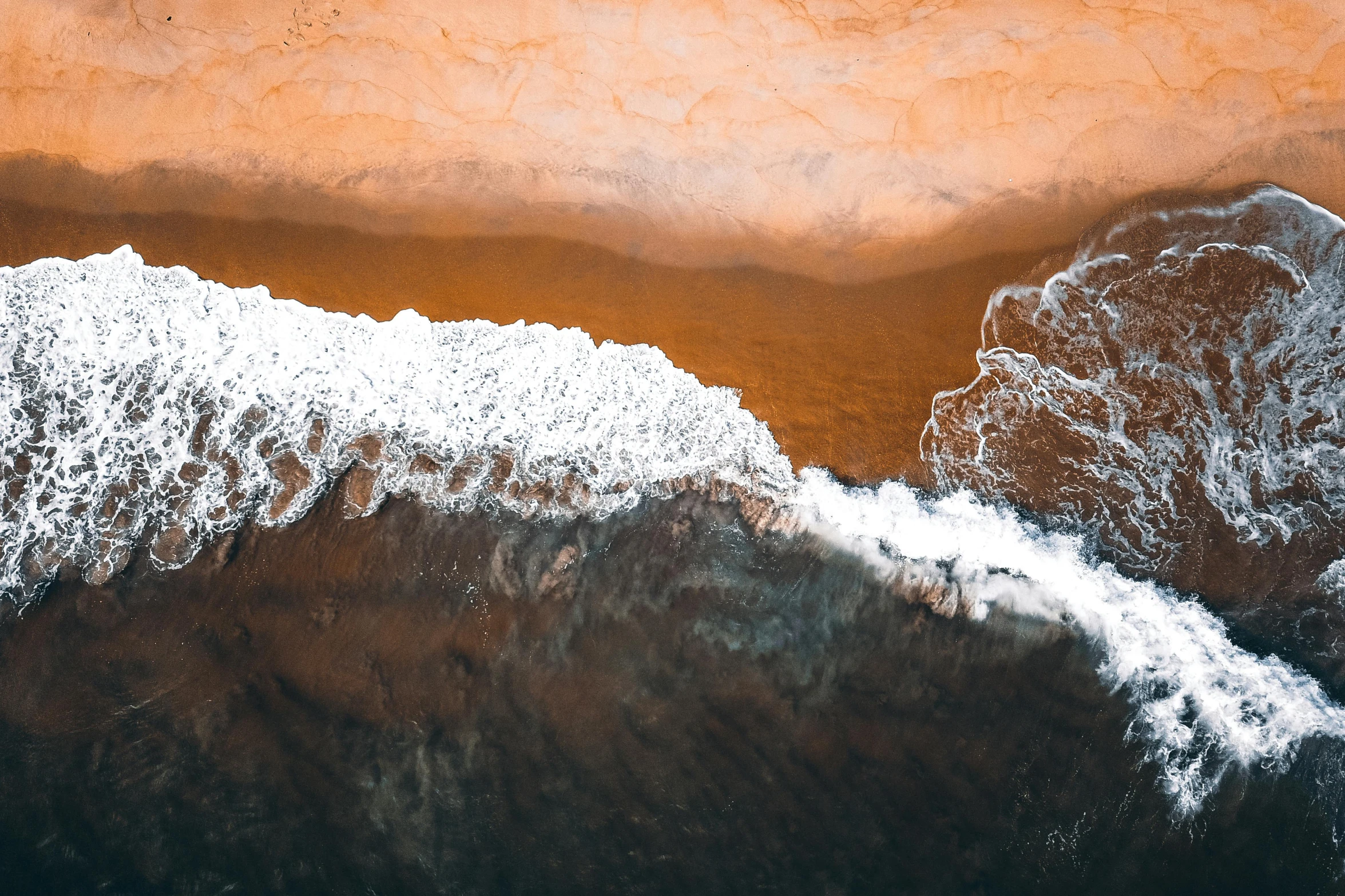 a person riding a surfboard on top of a sandy beach, by Daniel Lieske, pexels contest winner, minimalism, chocolate river, view from helicopter, dark sienna and white, both bright and earth colors