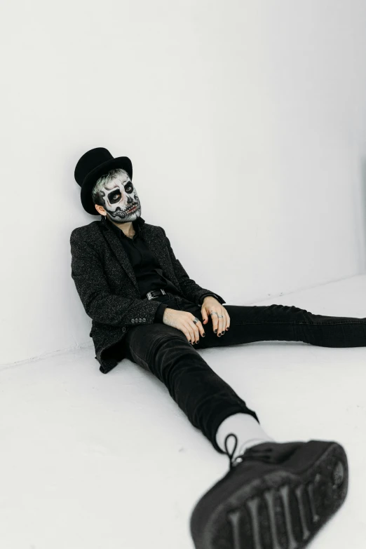 a man with a skeleton face sitting on the floor, inspired by Taro Yamamoto, trending on pexels, black top hat, style of seb mckinnon, wearing a mask, with a white background