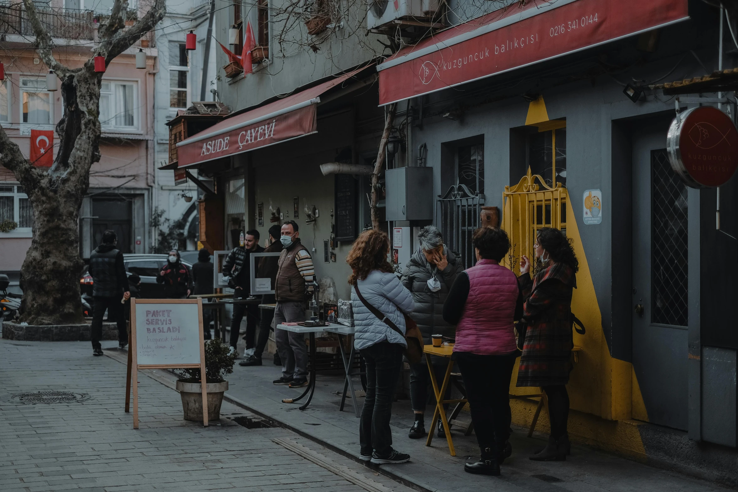 a group of people standing outside of a building, in a sidewalk cafe, istanbul, background image, nuri iyem